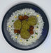 Plated dish with rice, green balls, and brown cubes on a white background