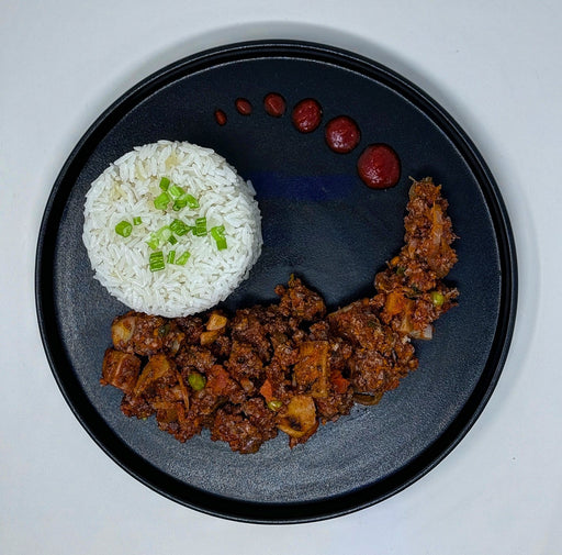 Plated dish with rice and meat on a black plate
