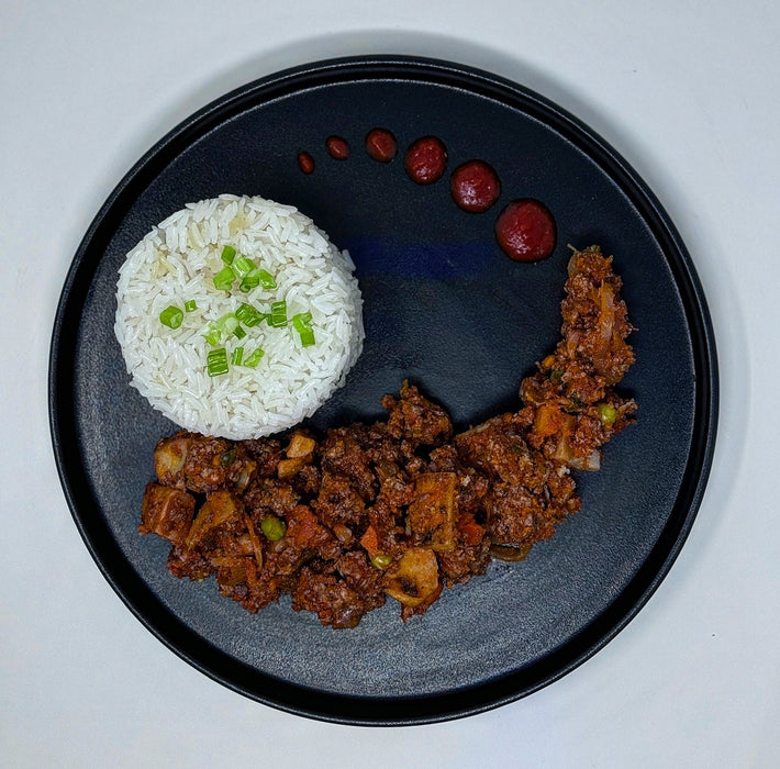 Plated dish with rice and meat on a black plate