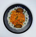 Plate of food with rice, orange dish, and green vegetables on a white background