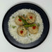 Four meatballs with green beans and red sauce on a bed of white rice in a black bowl.