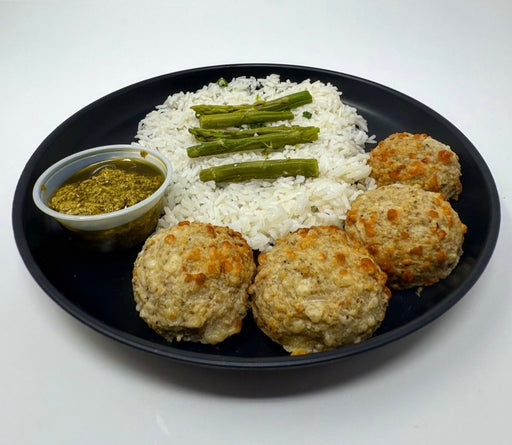 Spartan meal preps nj - pesto chicken meatballs - nj meal prep - 4 chicken meatballs paired with jasmine rice , asparagus and a pesto sauce cup served on a black plate. 