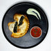 Pastry with spinach filling on a black plate with dipping sauces
