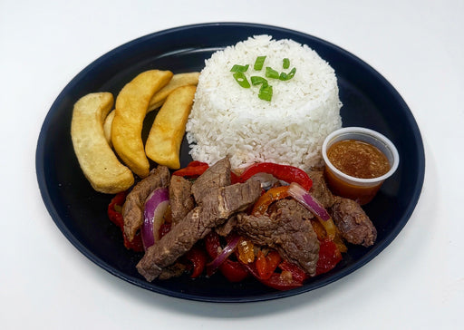 Plated dish with rice, steak, vegetables, and plantains on a white background