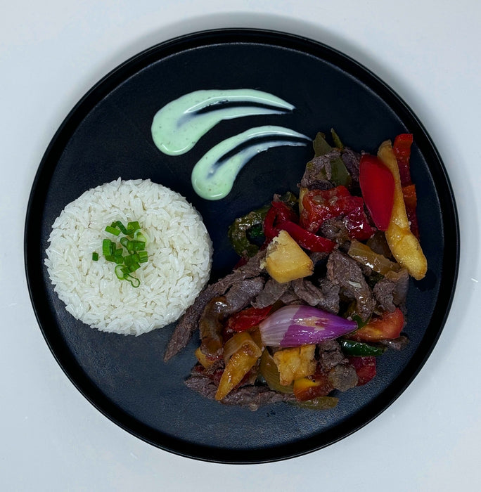Plated dish with rice, steak, vegetables, and plantains on a black plate. Healthy meal made by spartan meal preps new jersey.
