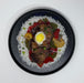 Plated dish with meat, vegetables, and a hard-boiled egg on a bed of rice.