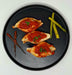 Three pieces of chicken breast with tomato sauce on a black plate with asparagus on a white background