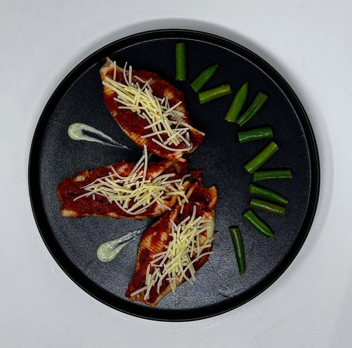 3 stuffed shells on a black plate with green beans next to it, this meal is made by spartan meal preps new jersey