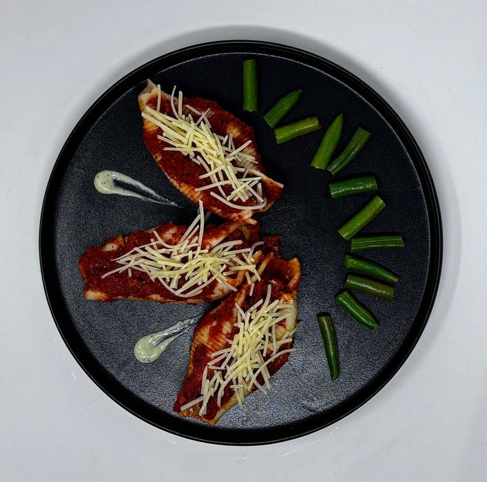 3 stuffed shells on a black plate with green beans next to it, this meal is made by spartan meal preps new jersey