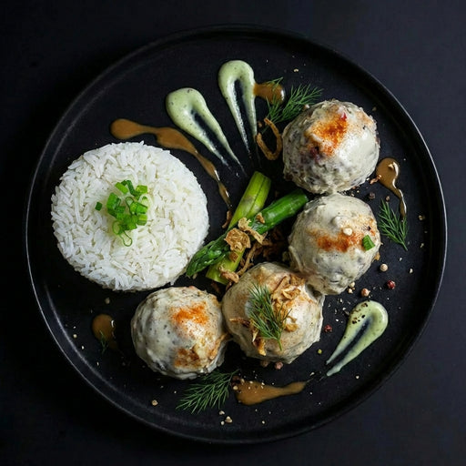 Plated dish with meatballs, asparagus, and rice on a dark background