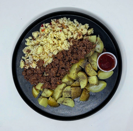 Plate of scrambled eggs, ground meat, potatoes, and a side of ketchup on a white background