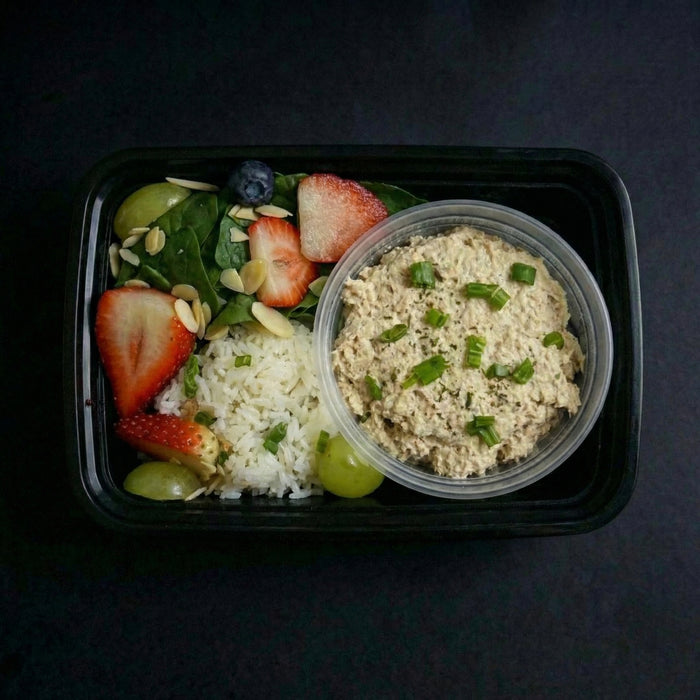 Meal container with salad and rice on a dark background