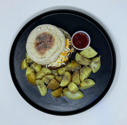 Plated meal with a sandwich and potatoes on a black plate