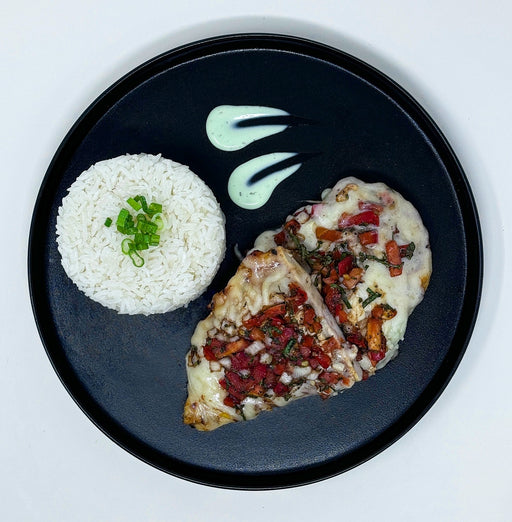 Plated dish of chicken with tomato sauce over white rice on a dark plate.
