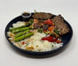 A plate of Korean Teriyaki steak bowl with jasmine rice, mixed vegetables, and steak, served with a side sauce.