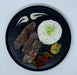 Steak with rice and vegetables on a black plate