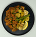 Black plate with fried tofu and vegetables on a white background