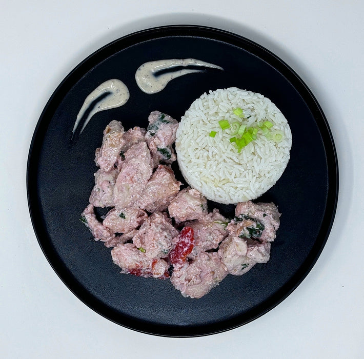 Black plate with fried chicken and white rice on a light gray background