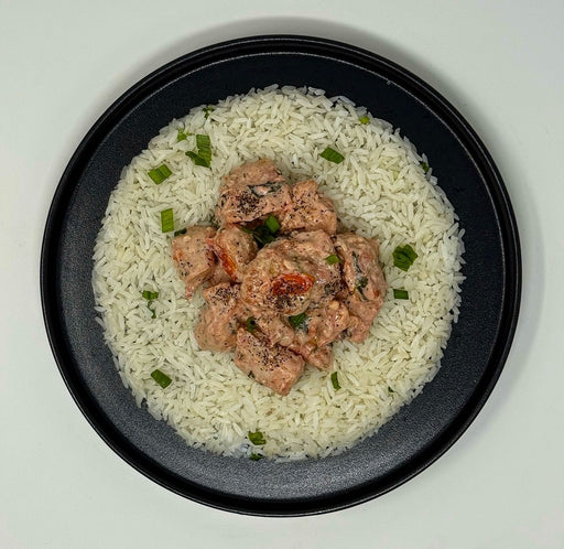 Plated dish of rice with chicken and green onions on a white background