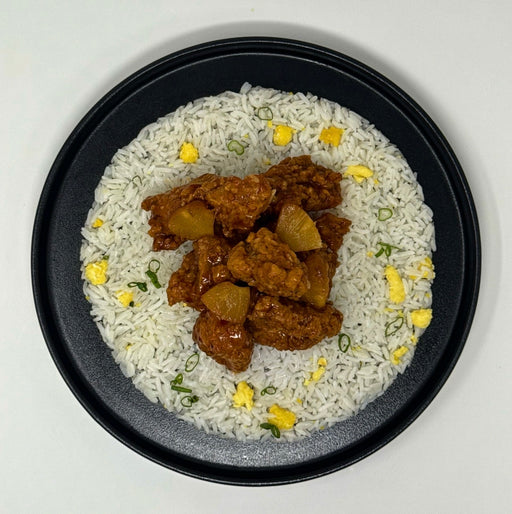Plated dish of rice with chicken and pineapple pieces on a white background
