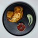 two teriyaki stuffed empanadas on a black plate with a house sauce. Healthy meal made by spartan meal preps a new jersey meal delivery company. 