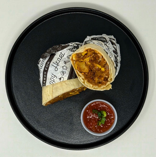 Burrito on a black plate with salsa on a white background
